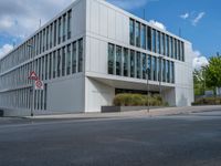 the building has a lot of glass windows on it, along with trees and bushes outside