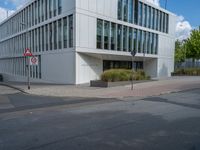 the building has a lot of glass windows on it, along with trees and bushes outside