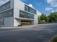 the building has a lot of glass windows on it, along with trees and bushes outside