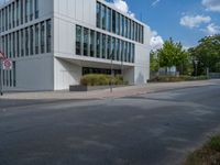 the building has a lot of glass windows on it, along with trees and bushes outside