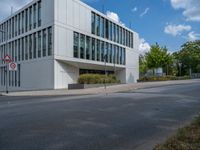 the building has a lot of glass windows on it, along with trees and bushes outside