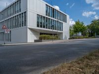 the building has a lot of glass windows on it, along with trees and bushes outside