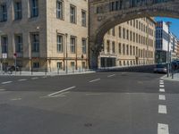 an archway with some windows to provide a light in the distance on a street corner