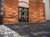 a sidewalk with chairs next to the brick building on the side, some have stairs and some buildings in the background