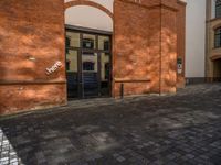 a sidewalk with chairs next to the brick building on the side, some have stairs and some buildings in the background