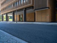 a road through which is a large modern building with an awning over it's entrance