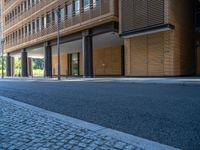 a road through which is a large modern building with an awning over it's entrance