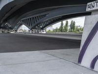 a very long cement road with some buildings and a few people on it, one is riding a skateboard