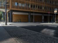 a road through which is a large modern building with an awning over it's entrance