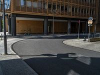 a road through which is a large modern building with an awning over it's entrance