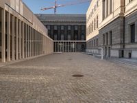 a brick courtyard with construction cranes in the background on a sunny day, in europe