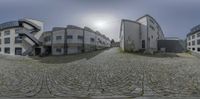 a large fisheye lens reflects the sky over an urban setting with apartments and a bicycle