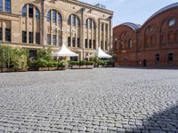 the building is large and red brick and has white umbrellas in front of it