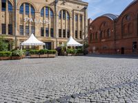 the building is large and red brick and has white umbrellas in front of it