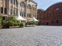 the building is large and red brick and has white umbrellas in front of it