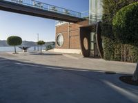 view of outdoor area with benches and bridge, surrounding concrete building and sidewalk with trees