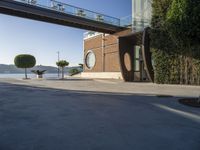 view of outdoor area with benches and bridge, surrounding concrete building and sidewalk with trees