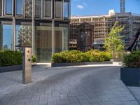 the side walk of a glass office building with concrete bricks and landscaping on each floor