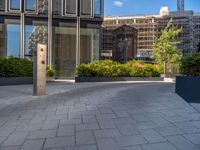 the side walk of a glass office building with concrete bricks and landscaping on each floor