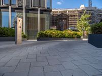 the side walk of a glass office building with concrete bricks and landscaping on each floor