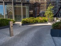 the side walk of a glass office building with concrete bricks and landscaping on each floor