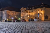 several buildings, parked cars and a fire hydrant in the middle of a cobblestone street