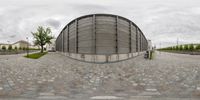 a large round concrete structure on the street outside of a building in europe with cobblestone