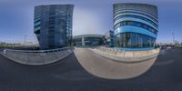 a fish eye lens photo of some office buildings and a skateboard ramp under a clear blue sky