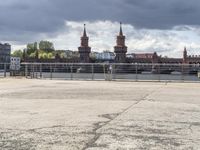 a man is playing tennis in front of a building and bridge on a cloudy day