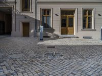 an empty parking lot with plants in the ground and on the side of the building, there is an enclosed area and windows