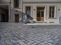 an empty parking lot with plants in the ground and on the side of the building, there is an enclosed area and windows