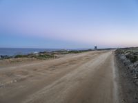 a beach at twilight with a sign on the side of road that warns to not go where