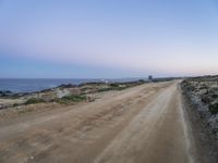 a beach at twilight with a sign on the side of road that warns to not go where