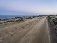 a beach at twilight with a sign on the side of road that warns to not go where