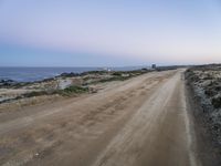 a beach at twilight with a sign on the side of road that warns to not go where