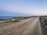 a beach at twilight with a sign on the side of road that warns to not go where