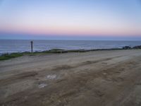 a beach at twilight with a sign on the side of road that warns to not go where