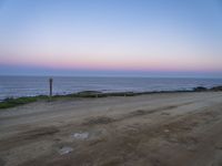 a beach at twilight with a sign on the side of road that warns to not go where