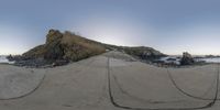 a small hill that looks like a rock formation next to the ocean with rope wrapped around