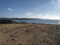 a beach with a field and water on it's side and rocks, grass, and grass