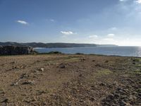 a beach with a field and water on it's side and rocks, grass, and grass