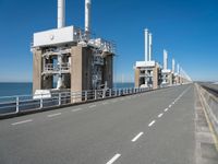 road going along side of two large buildings with air vents in the background and a view on a beautiful blue ocean