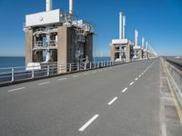 road going along side of two large buildings with air vents in the background and a view on a beautiful blue ocean