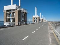 road going along side of two large buildings with air vents in the background and a view on a beautiful blue ocean