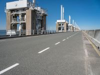 road going along side of two large buildings with air vents in the background and a view on a beautiful blue ocean