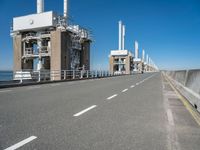 road going along side of two large buildings with air vents in the background and a view on a beautiful blue ocean