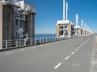 road going along side of two large buildings with air vents in the background and a view on a beautiful blue ocean