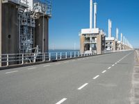 road going along side of two large buildings with air vents in the background and a view on a beautiful blue ocean