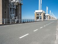 road going along side of two large buildings with air vents in the background and a view on a beautiful blue ocean