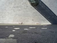 a building made out of white bricks has some white chairs in it next to a concrete wall